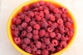 ripe raspberries in a yellow container on the table