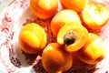 Ripe raw apricots in a plate on the table on a sunny day, close-up, vertical. Pile of fresh whole juicy orange apricots and