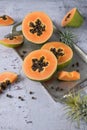 Ripe raw sliced papaya pawpaw fruit on vintage silver metallic tray with tillandsia plants on rustic ston
