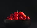 Ripe red acerola cherries fruit in a ceramic bowl with a black background. Royalty Free Stock Photo