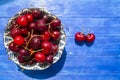 Ripe red cherries bowl with water drops on blue wooden table. Top view with copy space Royalty Free Stock Photo