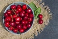 ripe red cherry berries in a round blue bowl on a dark background and mat Royalty Free Stock Photo