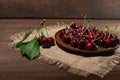 A ripe red cherry in a bowl and next to it on a wooden table Royalty Free Stock Photo