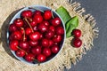 ripe red cherry berries in a round blue bowl on a dark background and mat Royalty Free Stock Photo