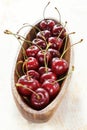 Ripe red cherry with water drops in a wooden elongated plate on an old painted table close up Royalty Free Stock Photo