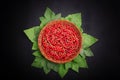 Ripe red currant in a basket on a black background. Juicy bright red berries with green leaves. Fresh tasteful currant. Royalty Free Stock Photo
