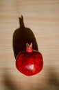 Ripe red fruit pomegranate on light wooden table under the direct rays of the sun and hard long shadow, vertically view Royalty Free Stock Photo