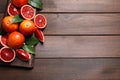 Ripe red oranges, green leaves and board on wooden table, top view. Space for text Royalty Free Stock Photo