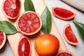 Ripe red oranges, green leaves and wooden board on light table, flat lay Royalty Free Stock Photo