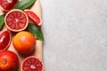 Ripe red oranges, green leaves and wooden board on light table, top view. Space for text Royalty Free Stock Photo
