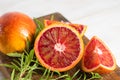 Ripe red oranges on wooden background. Sliced ripe juicy Sicilian Blood oranges on white wooden background