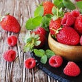 ripe red raspberries and strawberries in wooden bowl, selective focus Royalty Free Stock Photo