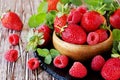 Ripe red raspberries and strawberries in wooden bowl, selective focus Royalty Free Stock Photo