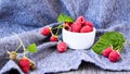 Ripe red raspberries in white bowl with green leaves on wooden background. Copy space Royalty Free Stock Photo