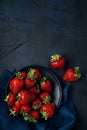 Ripe red strawberries in a black plate with blue napkin on dark blue background. Top view. Space for text Royalty Free Stock Photo