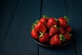 Ripe red strawberries in a black plate on a dark blue wooden Background. Sweet dessert from fresh berries Royalty Free Stock Photo