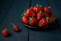 Ripe red strawberries in a black plate on a dark blue wooden background. Sweet dessert from fresh berries on  table Royalty Free Stock Photo