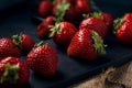 Ripe red strawberries with black serving board on burlap and dark blue background. Sweet dessert from fresh berries on the table Royalty Free Stock Photo