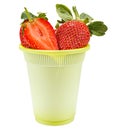 Ripe red strawberries with green leaves and half of cutted strawberry on top in a green disposable cup made of biodegradable Royalty Free Stock Photo