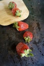 Ripe, red strawberries with water drops splash and wooden cutting board on dark background. Top view. Royalty Free Stock Photo