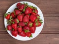 Ripe red strawberries on a white plate on a wooden table copispace, Flatley