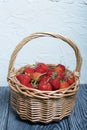 Ripe red strawberries in a wicker basket. Against the background of pine boards painted in white and black. Harvest 2020 Royalty Free Stock Photo