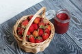 Ripe red strawberries in a wicker basket. Nearby is an open can of strawberry jam. Against the background of pine boards painted Royalty Free Stock Photo