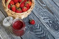 Ripe red strawberries in a wicker basket. Nearby is an open can of strawberry jam. Against the background of pine boards painted Royalty Free Stock Photo