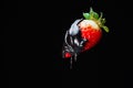 Ripe red strawberry berry in hot chocolate on a black background Royalty Free Stock Photo
