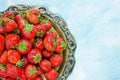Ripe red strawberry on old vintage copper tray on blue background blank space for text