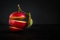 Ripe red sliced apple with a leaf in a levitation stack on a black concrete surface against a dark background. moody creative Royalty Free Stock Photo