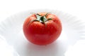 A ripe red tomato with water drops on the plate isolated on a white background