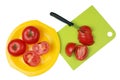 Ripe red tomatoes are cut with a sharp knife on a plastic kitchen board