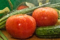 Ripe red tomatoes, green cucumbers, green onion feathers are covered with large drops of water Royalty Free Stock Photo