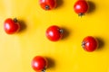 Ripe red tomatoes with green leaves isolated on yellow background. Top view Royalty Free Stock Photo