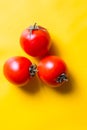 Ripe red tomatoes with green leaves isolated on yellow background. Top view Royalty Free Stock Photo