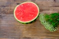 Ripe red watermelon, cut in half, home cooking concept, white wildflowers, wooden table, texture of natural background, delicious