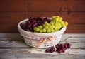 Ripe red and white grapes in basket on aged wooden surface. Royalty Free Stock Photo