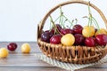 Ripe red and yellow cherries with water drops in a vintage wicker basket on a wooden table with white background Royalty Free Stock Photo