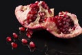 Ripe ruby juicy broken pomegranate with grains on black background with reflection. Selective focus