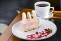 Ripe sea buckthorn mousse dessert with caramel biscuit served on a white plate with a cup of tea