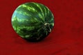 Ripe single full watermelon berry on red cloth napkin on the table, selective focus