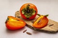 Ripe single persimmon. Fresh whole fruit, half sliced, seeds. Wooden cutting board, stone concrete background Royalty Free Stock Photo