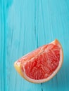 Ripe slice of pink grapefruit citrus fruit on turquoise wooden background. Close up, copy space. Natural food Royalty Free Stock Photo