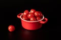 Ripe small cherry tomatoes in a red square ceramic baking dish on black background Royalty Free Stock Photo