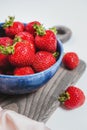 Ripe strawberries in blue bowl on rustic wooden board, elegant style, sweet berry for summer dessert. Filled bowl or plate by red Royalty Free Stock Photo