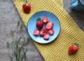 Ripe strawberries on a blue saucer on a yellow napkin background, top view Royalty Free Stock Photo