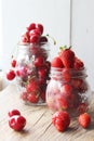 Ripe strawberries and cherries , glass jars. Wood background, rustic style. Royalty Free Stock Photo