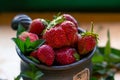 Ripe strawberries lie in a brown mug along with mint leaves on a wooden table among mint leaves