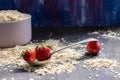 Ripe strawberries in an old spoon with oatmeal scattered around on a wooden table Royalty Free Stock Photo